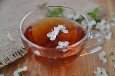 Çiçeklerle ahşap bir masada bir fincan çay.