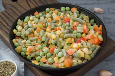 Baharatile kaynayan bir tavada dondurulmuş doğranmış sebzeler. Vegan gıda. 