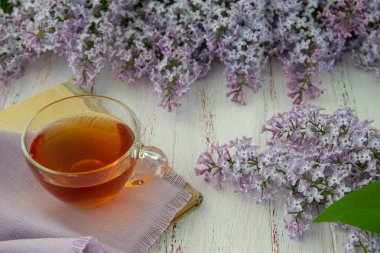 Leylak ve yapraklarıbahar çiçekleri , ahşap bir arka plan üzerinde çay bir fincan. Dekoratif çerçeve, üst görünüm.