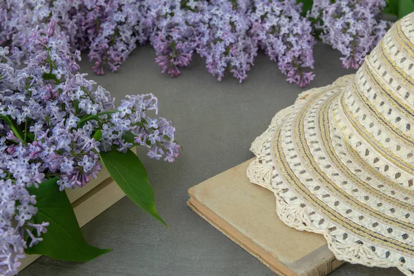 Spring flowers of lilac and leaves, book and hat . Decorative frame, top view.
