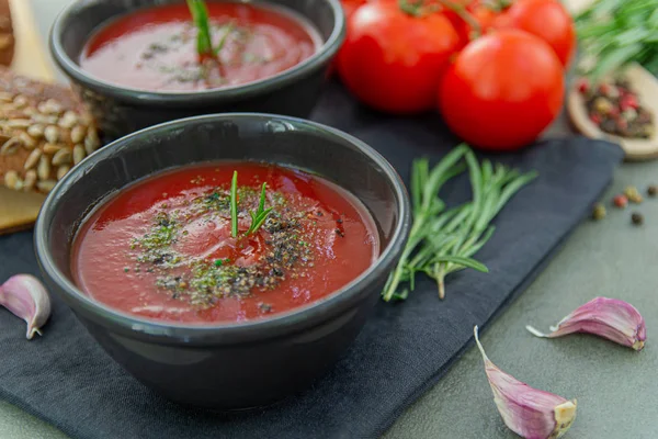 Cold tomato gazpacho soup in a deep plate on a stone background. Traditional Spanish cuisine. The concept of Spanish cold soup of ripe tomatoes.