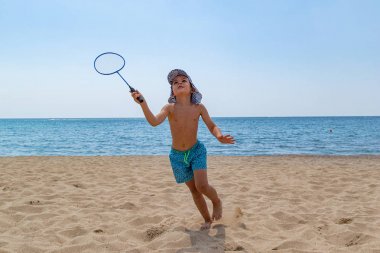 Çocuk badminton raketi ve plajda bir mekik ile oynar. Aile tatili kavramı. Boşluk Kopyala.