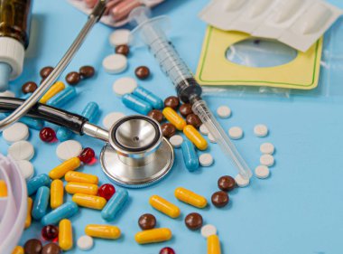 Sağlık ve tıp kavramı. Çeşitli ilaç tabletleri, stetoskop ve hap kutuları mavi arka plan üzerinde. Dağıtım ve hap alarak hatırlatma
