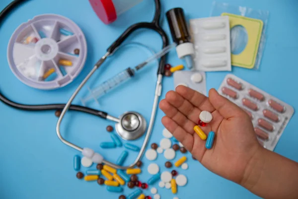The concept of health and medicine.  Assorted pharmaceutical tablets, stethoscope and pill boxes on blue background. Distribution and reminder of taking the pill