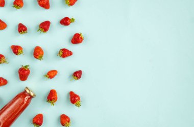 Pastel mavi tonlarda cam bir şişede çilek ve çilek karışımının yaratıcı yaz şablonu. Meyve asgari konsept. Üst manzara, düz uzanma