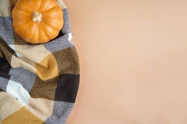 Sonbahar kompozisyonu Flatlay. Turuncu balkabağı, ekose, kuru sonbahar yaprakları, pastel bej arka planda koniler. Sonbahar minimalizmi konsepti, afiş. Düz yatak, üst manzara..