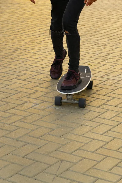 La imagen recortada del joven es el monopatín en la ciudad. Adolescente masculino con monopatín — Foto de Stock