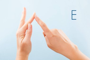 Fingerspelling alfabesi. Sağır ve dilsiz Bsl Alfabe harf E gösterilen mavi arka plan üzerinde izole eller.