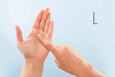 Fingerspelling alfabesi. Sağır ve dilsiz Bsl Alfabe harf L gösterilen mavi arka plan üzerinde izole eller.