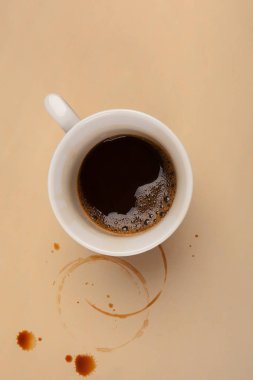 Yukarıdan bej masada fincan espresso kahve lekeleri. Fazla mesai.