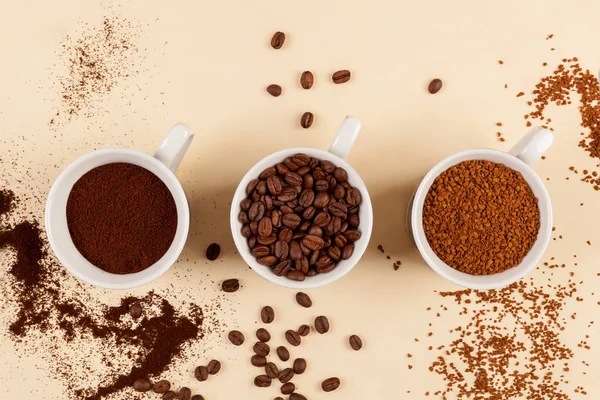 Various types of coffe - ground, instant and beans in three cups from above.