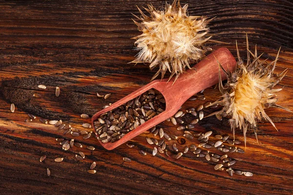 木製のテーブルの上からスプーンで種と粉ミルク アザミの花 マリアアザミ — ストック写真