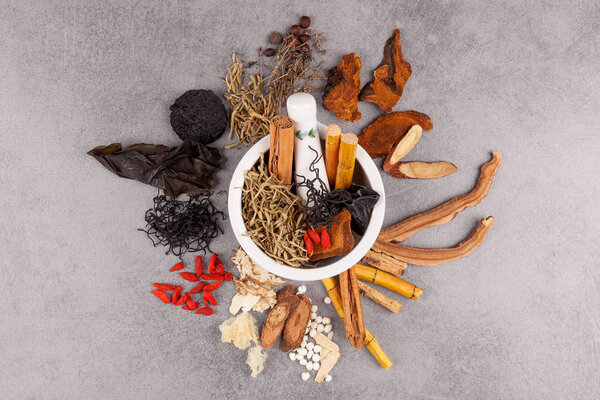 Different kind of Chinese herbal and mortar on gray background.