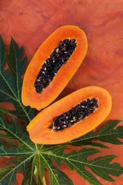 Yukarıdan turuncu beton üzerinde taze papaya meyve halfes. Tropikal meyve yeme. 