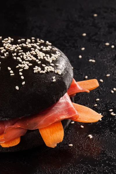 Burger Black Bun Ham Carrot Served Black Table Selective Focus — Free Stock Photo