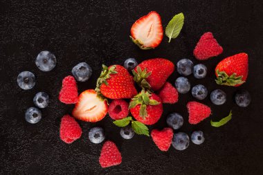 Siyah arka plan üzerine çeşitli taze yaz meyveleri. Çilek, yaban mersini ve ahududu. Sağlıklı yaz meyve, antioksidan.