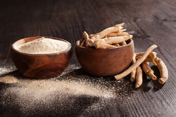 Ashwagandha Toz ve siyah arka plan üzerine ahşap bardak kökleri. Superfood, adaptogen, besin takviyesi.