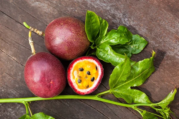 Ahşap masa üzerinde yukarıdan yapraklarla taze passionfruits.