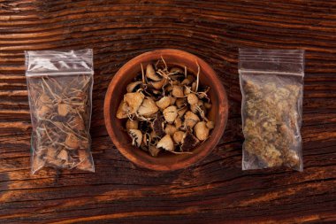 Kuru psilosibin sihirli mantar ve esrar tomurcukları kahverengi masada plastik torbalarda. Tıp alternatif çözüm.