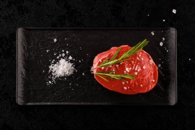 Siyah tablo ve koyu arka plan üzerinde lüks ham sığır eti biftek. Mutfak cousine.