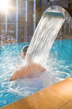 Yakışıklı adam ile su duş masaj hidroterapi doğa manzaralı büyük cam pencerelerle lüks otelin havuzunda rahatlatıcı.