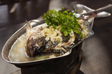 Bütün ızgara balık taze kişniş ve eski koyu ahşap masa üzerinde limon sosu ile baharat.