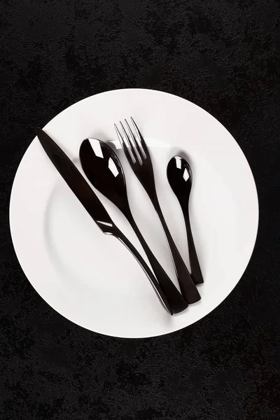 Μαύρο Μαχαιροπήρουνα Λευκό Πιάτο Από Πάνω Σκούρα Επιφάνεια Μοντέρνα Σχεδίαση — Φωτογραφία Αρχείου