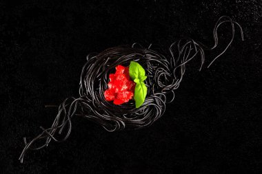 Squid mürekkep makarna sosları ve fesleğen ile siyah arka plan üzerine bırakır. Lüks mutfağı.