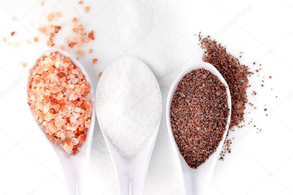 Different types of salts in spoons. Himalayan and kitchen salt isolated on white background from above.
