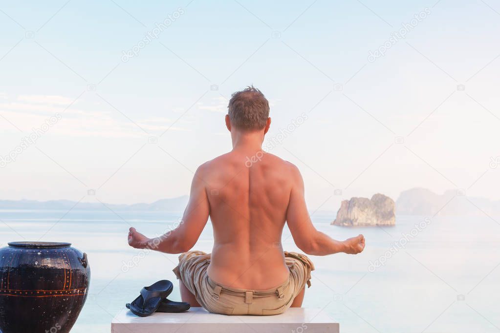 Young Man Meditating overlooking ocean.