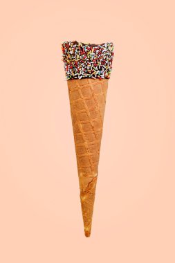 Empty cone with colored sugar and chocolate on a beige backgroun