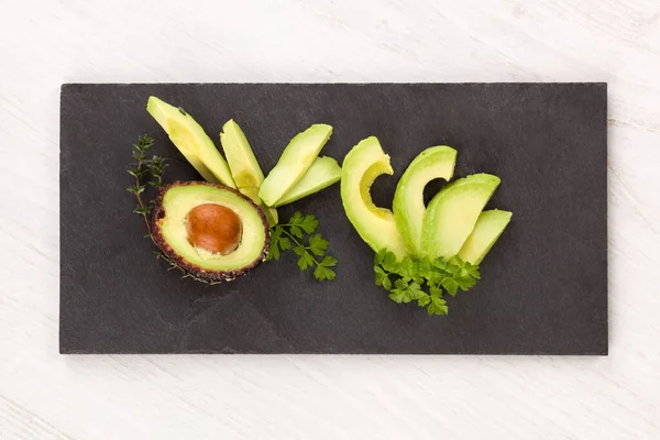 Avocado Fresco Intero Affettato Con Erbe Fresche Sfondo Nero Alimenti — Foto Stock