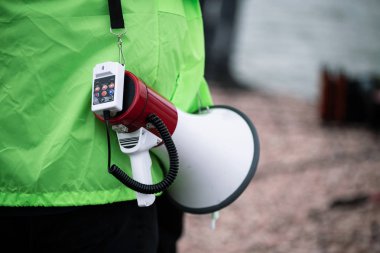 Bullhorn. Omzunda bullhorn olan yeşil ceketli bir adam..
