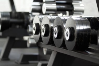 Spor salonunda rafta sıralar halinde metal halterler. Ağırlık eğitim ekipmanları.