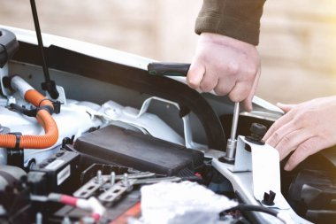 Oto tamircisi arabayı tamir ediyor. Bir arabanın cıvatasını söken tamircinin eli. Yakın çekim