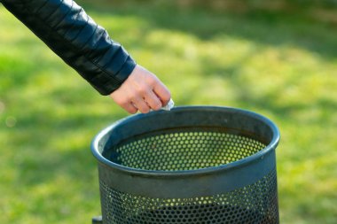 El yeşil bir çöp kutusuna götürmek için bir kağıt parçası tutarak