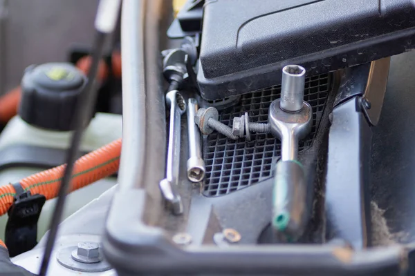 Professional mechanic tool lies on the windshield of an electric car