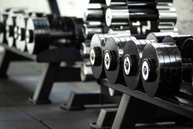 Spor aletleri. Siyah halter seti. Spor salonunda rafüzerinde birçok metal halter yakın.