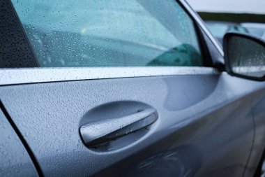 Yağmurdan sonra kapı arabasının ıslak kolunu kapatın. Araba kapı kolundasu düşer.