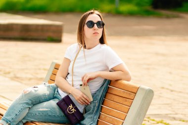 Cherkassy, Ukrayna- Mayıs 6, 2019: Güneş gözlüğü genç bir kız parkta ahşap bankta dinleniyor