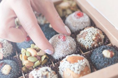 Kurutulmuş meyve, fındık, muz, hurma ve bal ile sağlıklı organik tatlılar ile kutu - vegan çiğ atıştırmalık. Kadın el bir vegan şeker alır.