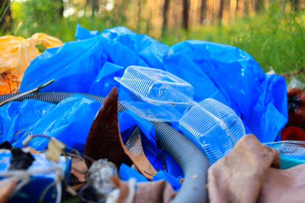 A package of plastic garbage lies in the forest on a forest road, pollution of nature, garbage and nature