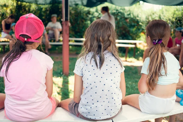 Children\'s meeting. Three girlfriend sitting on the meeting in the outdoor summer camp.
