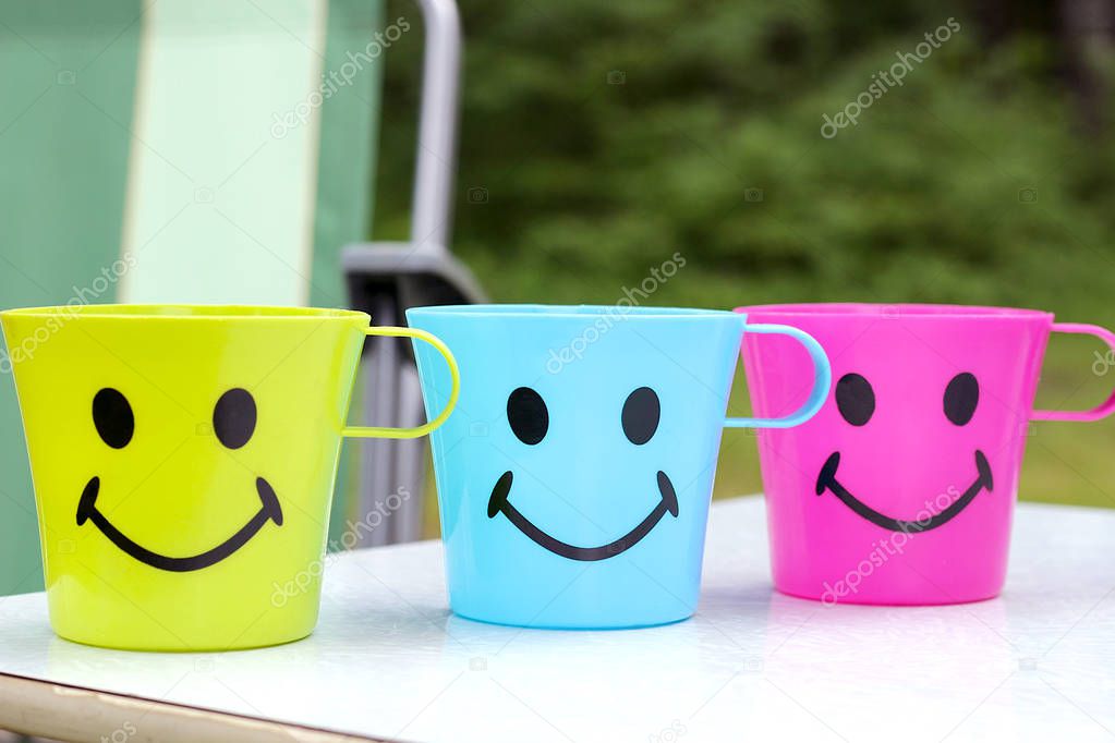 three plastic cups with an attractive face with a smile are stan