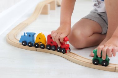 küçük çocuk çocuk oyun odasında raylar üzerinde alfabe tren ahşap harflerle oynar. buharlı tren, renkli vagonlar; doğal, çevre dostu malzemeden yapılmış ahşap oyuncak. erken çocukluk gelişimi, le