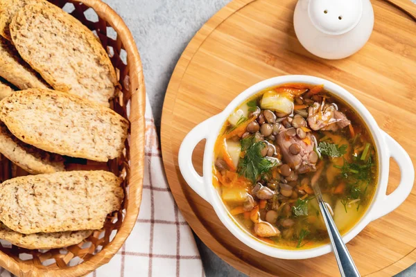 Tahta bir tahtanın üstünde tavuklu mercimek çorbası.