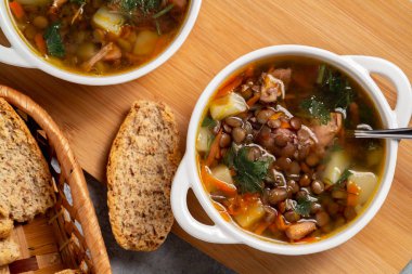 İki tabak mercimek çorbası ve ahşap bir tahtanın üstünde tavuk, üst manzara.