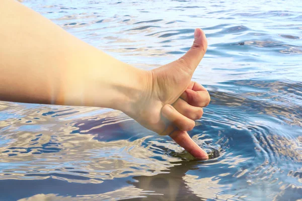 Vrouwelijke hand raakt het water met een vinger en laat zien dat het warm en schoon is. Zomervakantie en zwemconcept — Stockfoto