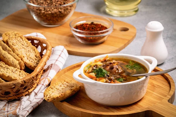 Sopa de lentejas con pollo en un tazón blanco sobre una tabla de madera sobre una mesa gris e ingredientes — Foto de Stock