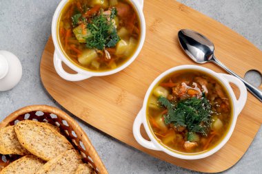 İki tabak mercimek çorbası ve ahşap bir tahtanın üstünde tavuk, üst manzara.